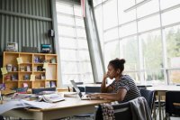 Focused high school student studying at laptop library